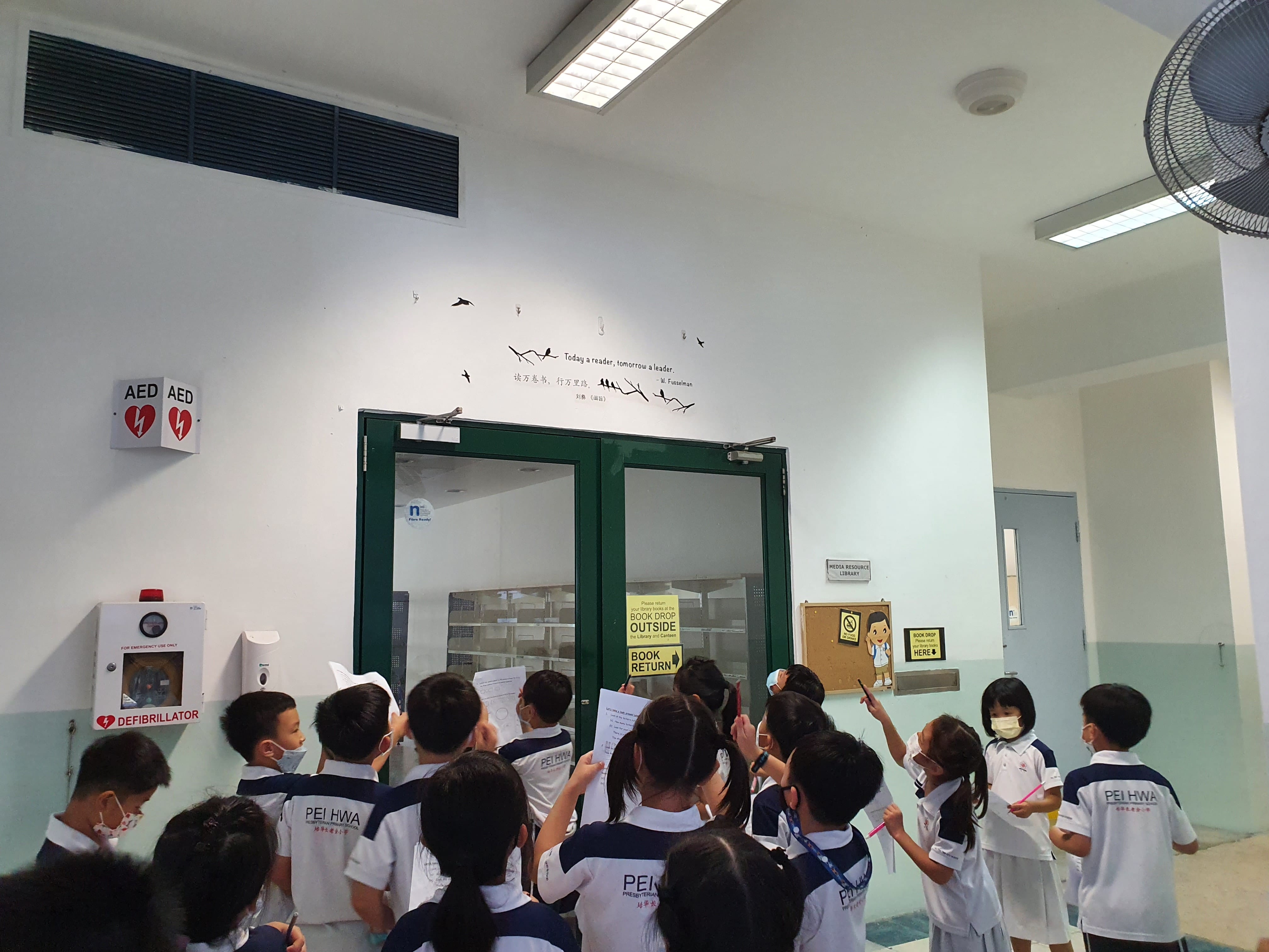 Students looked around outside the library to find the answer to the given task.